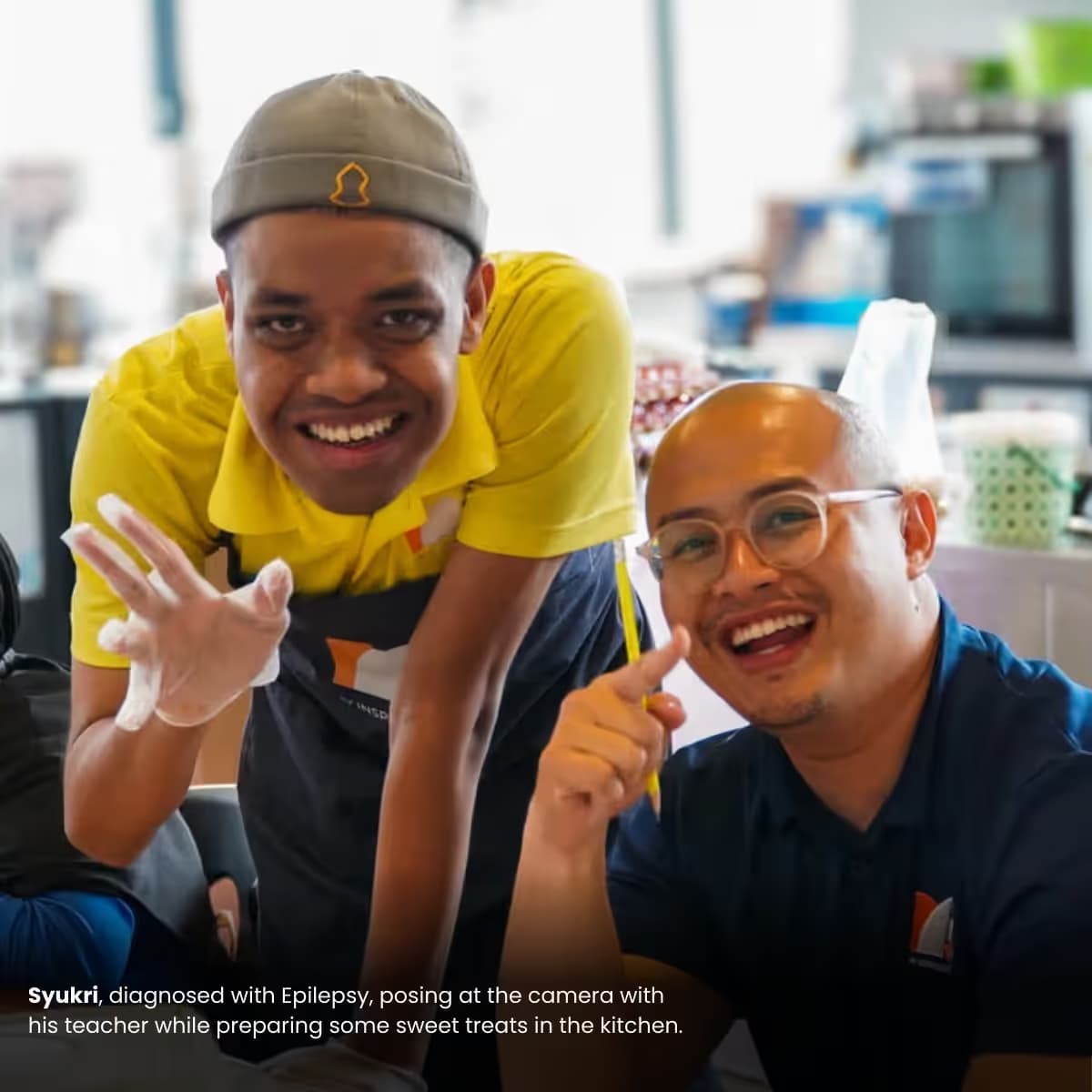 Syukri, diagnosed with Epilepsy, posing at the camera with his teacher while preparing some sweet treats in the kitchen.