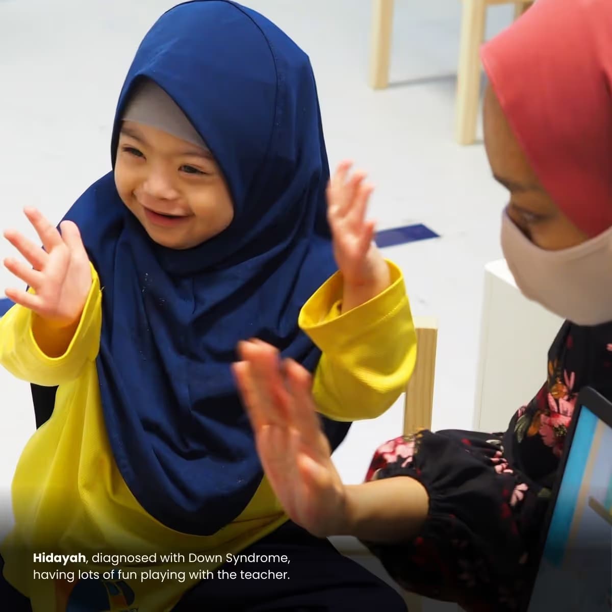 Hidayah, diagnosed with Down Syndrome, having lots of fun playing with the teacher.
